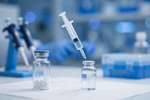 Lyophilized peptide vial and syringe drawing solvent in a research lab